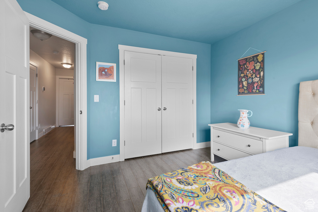 Bedroom with dark wood finished floors, a closet, and baseboards