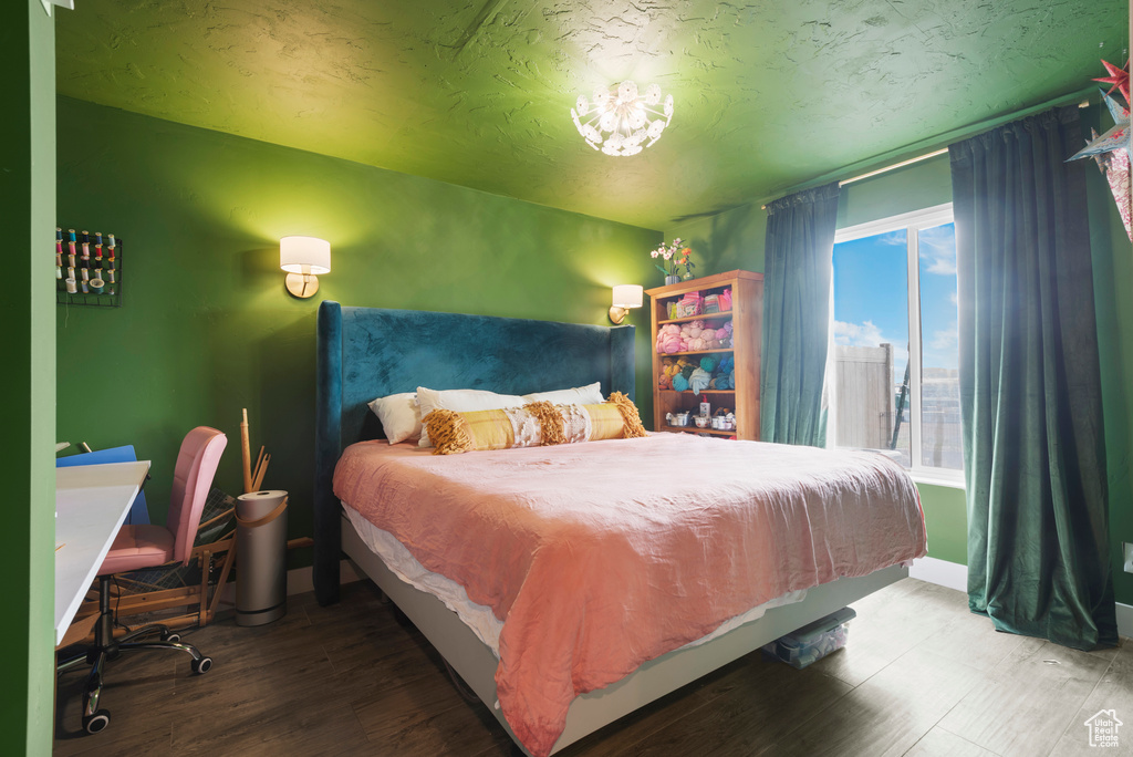 Bedroom with wood finished floors, a textured ceiling, and baseboards