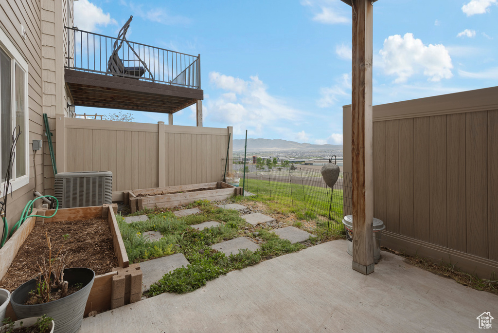 View of yard featuring central air condition unit, a patio, a mountain view, and a balcony