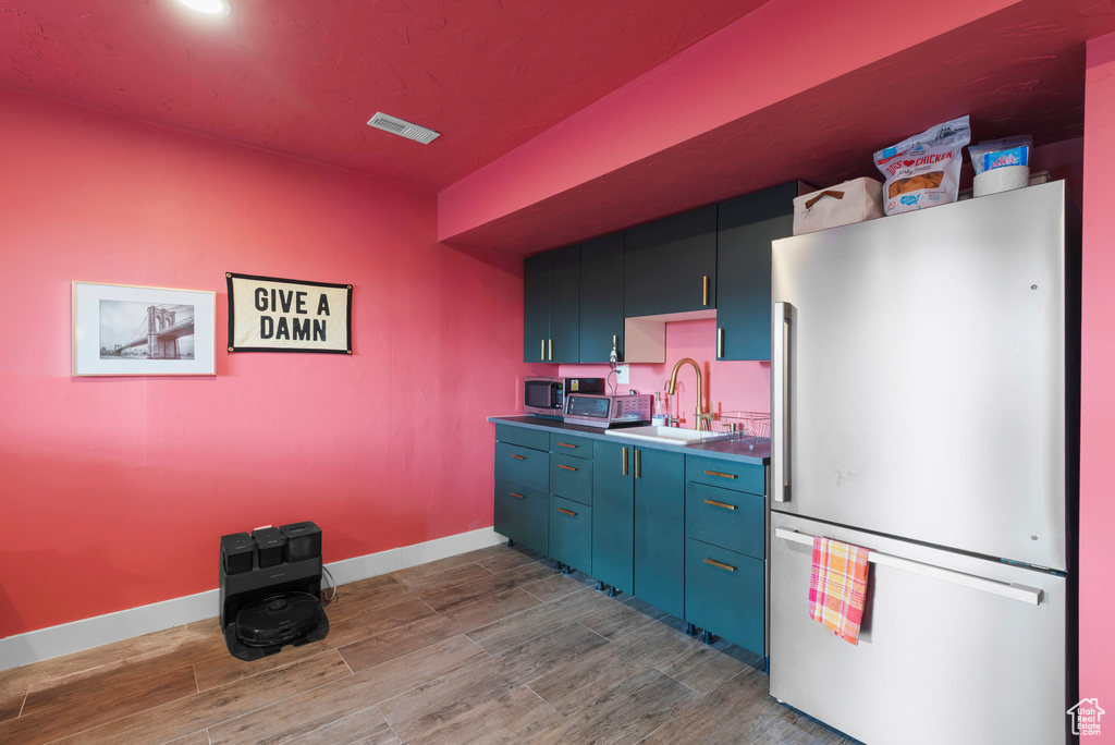 Kitchen with freestanding refrigerator, a sink, dark wood-style floors, baseboards, and stainless steel microwave