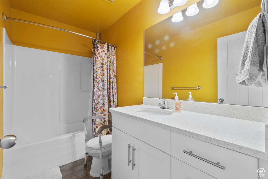 Full bathroom with vanity, toilet, shower / bathtub combination with curtain, and wood finished floors