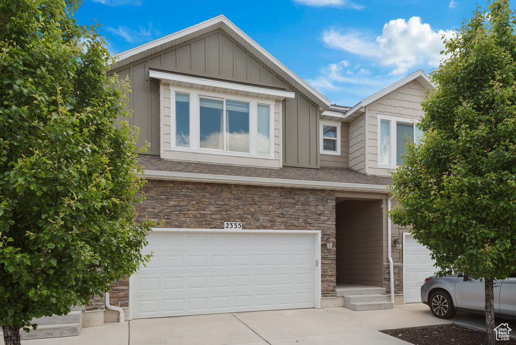 View of front of home featuring an attached garage, board and batten siding, concrete driveway, and stone siding