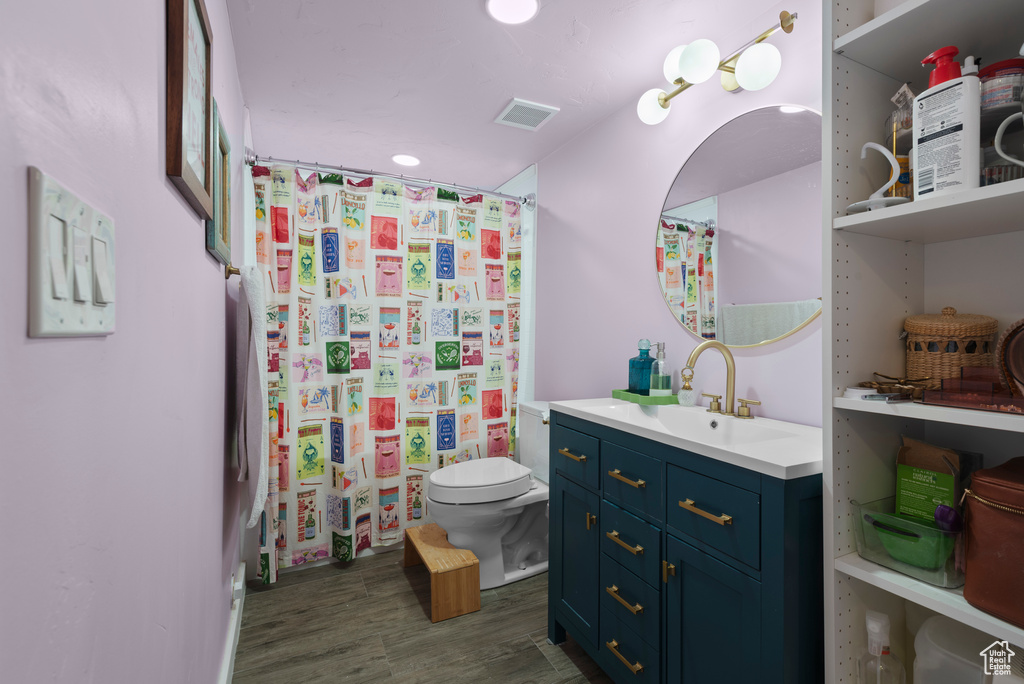 Bathroom featuring toilet, vanity, wood finished floors, and curtained shower