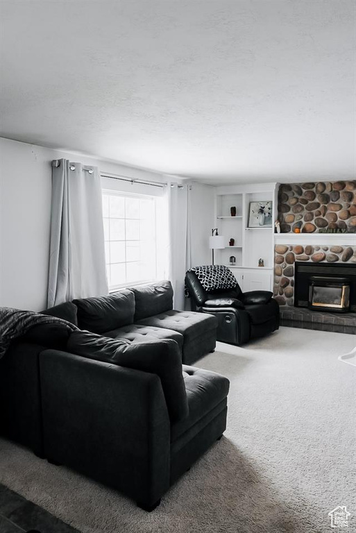 Living area featuring a stone fireplace and carpet