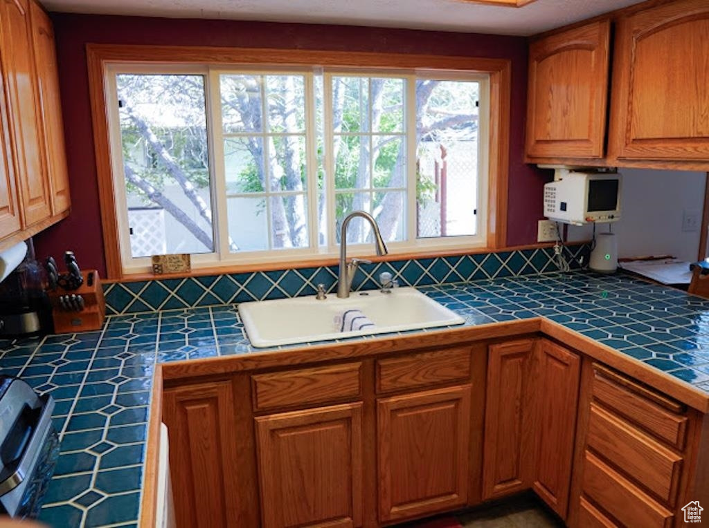 Kitchen featuring tile counters, a sink, and brown cabinetry