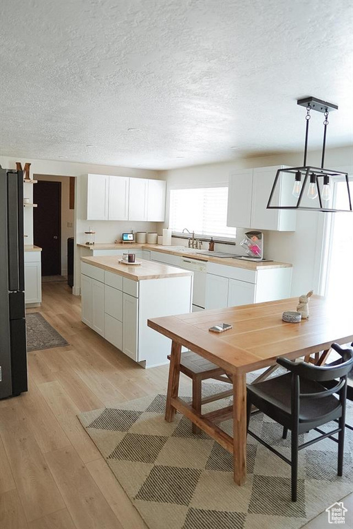 Kitchen featuring white cabinets, light wood-type flooring, light countertops, and a textured ceiling