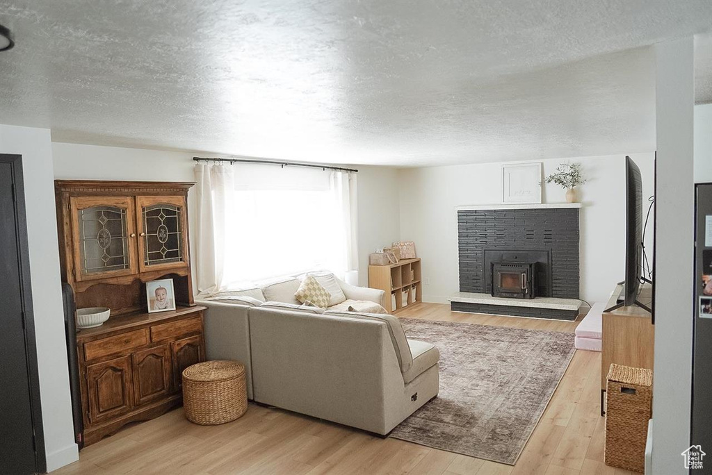 Living room featuring a textured ceiling, light wood finished floors, and a fireplace