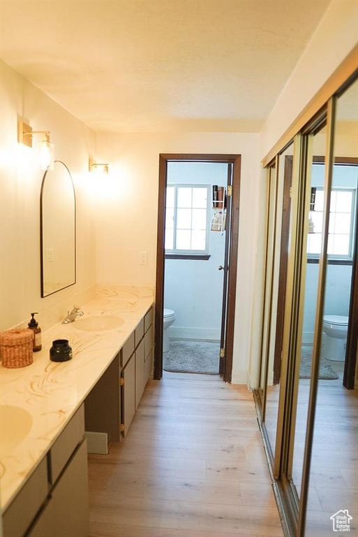Bathroom featuring toilet, double vanity, and wood finished floors