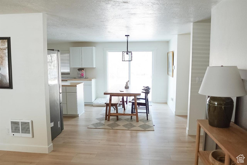 Dining space with light wood-style floors, baseboards, and a textured ceiling