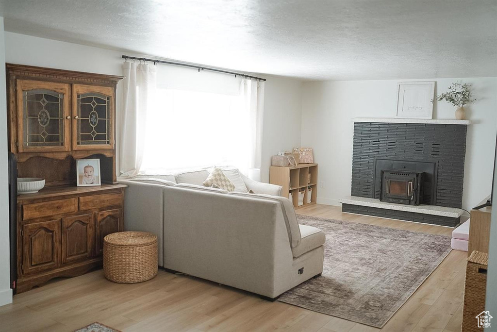 Living room featuring light wood-style flooring, a brick fireplace, and a textured ceiling