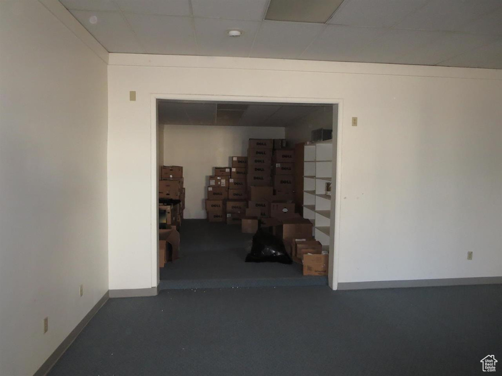 Hall featuring a paneled ceiling and baseboards
