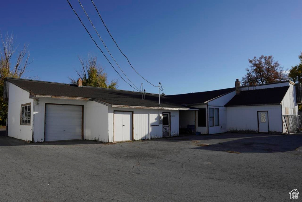 View of front of home with an attached garage, a chimney, and an outbuilding