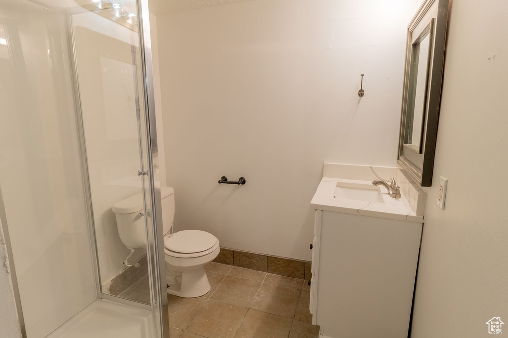 Full bath with vanity, toilet, a shower stall, and tile patterned flooring