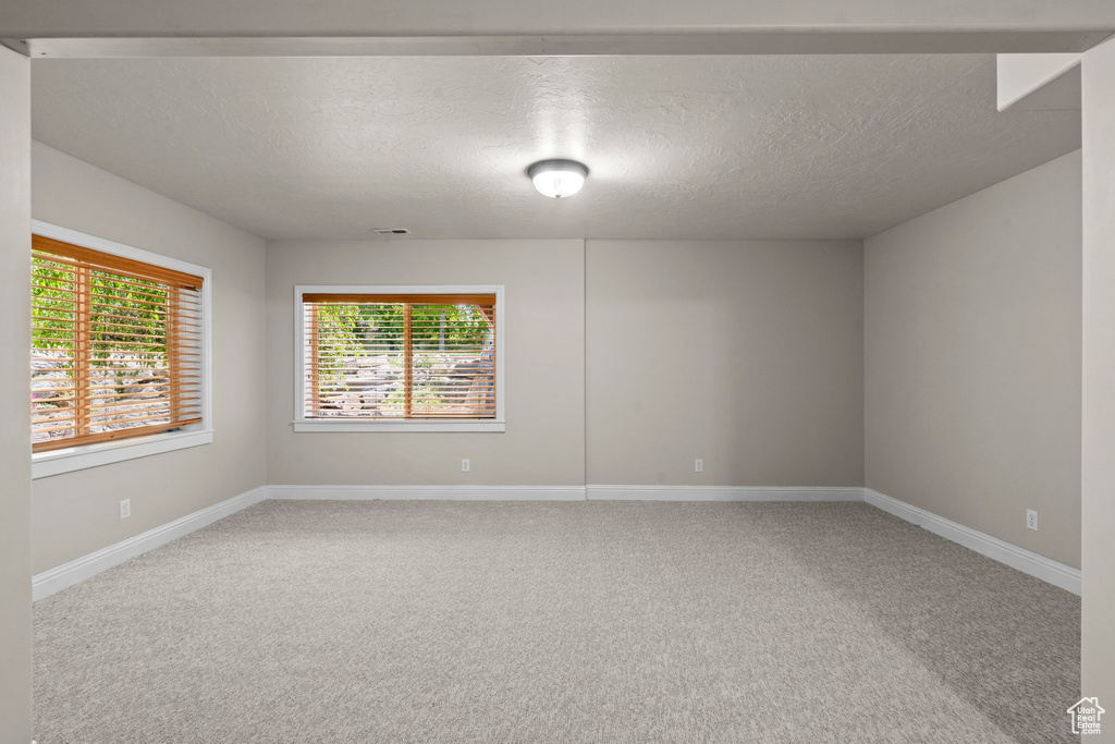 Spare room with carpet floors, a textured ceiling, and baseboards