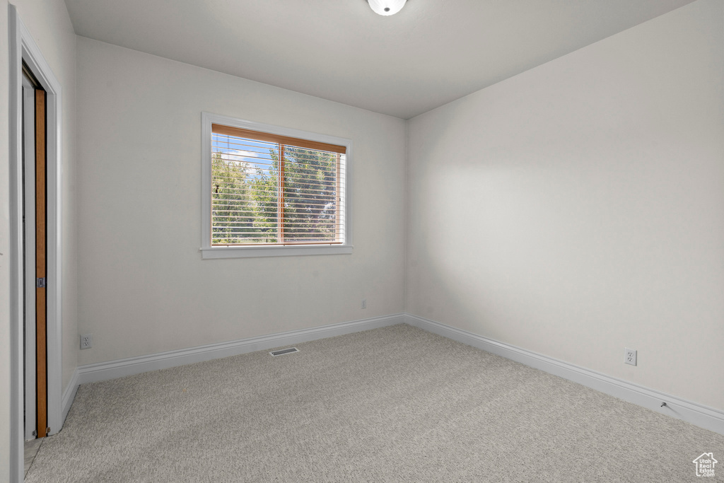 Empty room featuring light carpet and baseboards