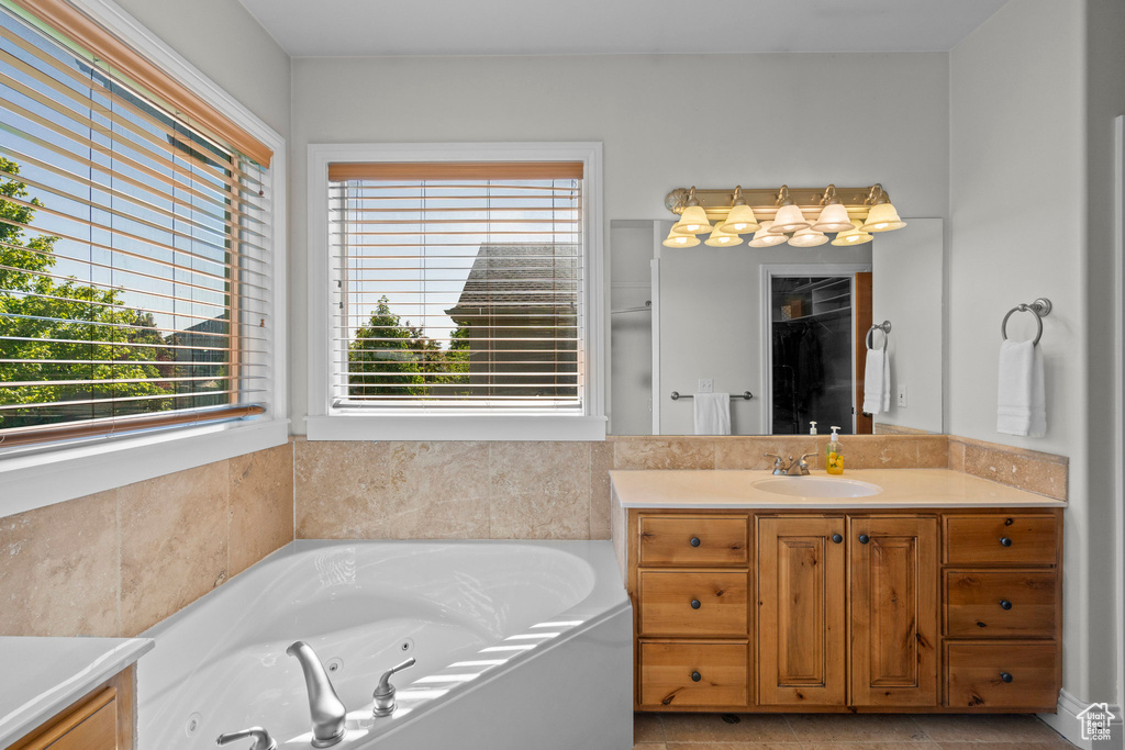 Full bath featuring plenty of natural light, vanity, and a tub with jets