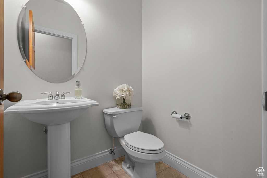 Half bath with toilet, baseboards, and tile patterned flooring