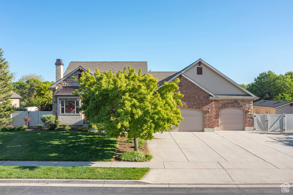 View of front of property featuring driveway, a garage, a gate, and a chimney