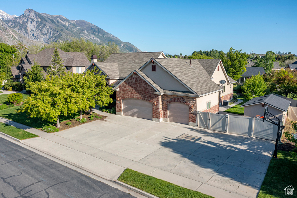 View of front of house featuring a gate, brick siding, concrete driveway, and an attached garage