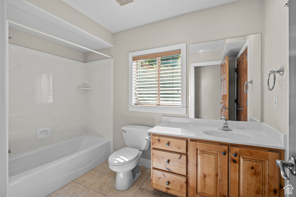 Bathroom with toilet, vanity, tile patterned floors, shower / washtub combination, and baseboards