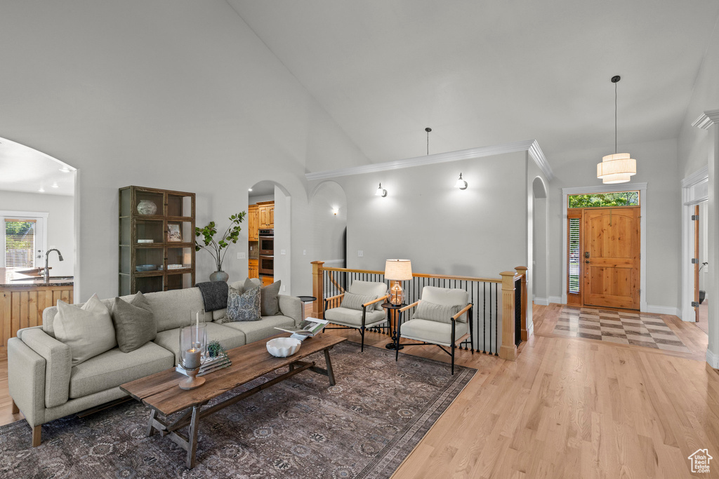 Living area with arched walkways, high vaulted ceiling, light wood-type flooring, and baseboards