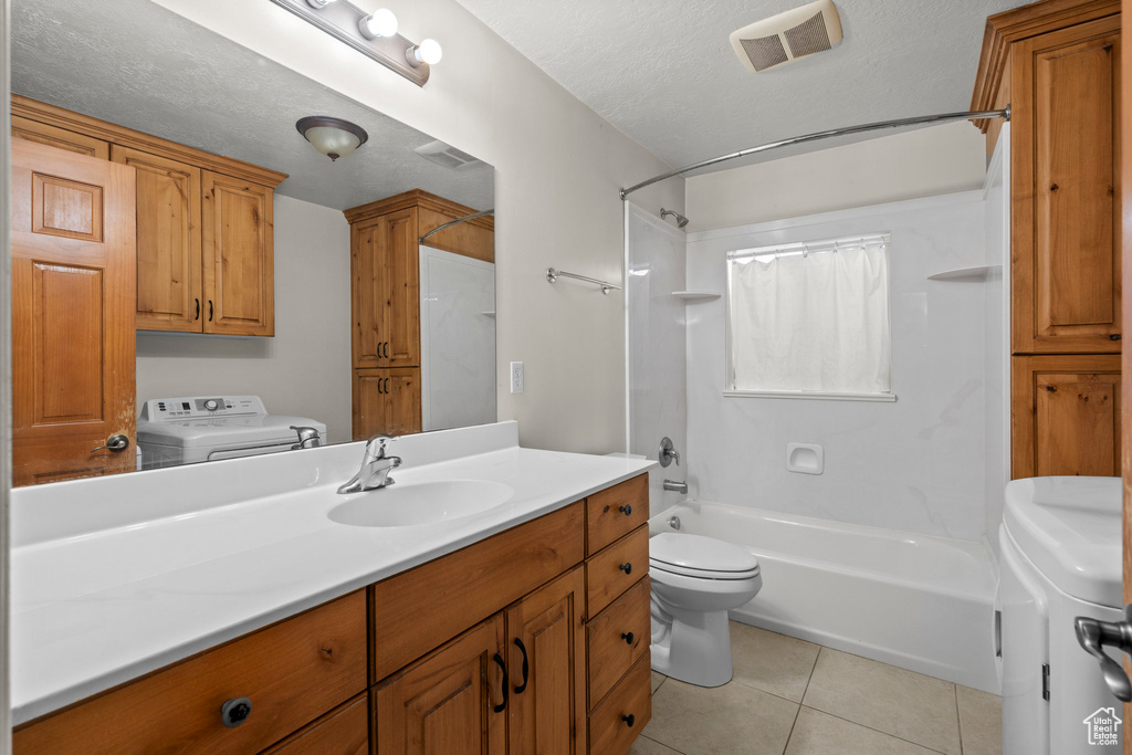 Bathroom featuring toilet, vanity, shower / bathtub combination, tile patterned floors, and independent washer and dryer