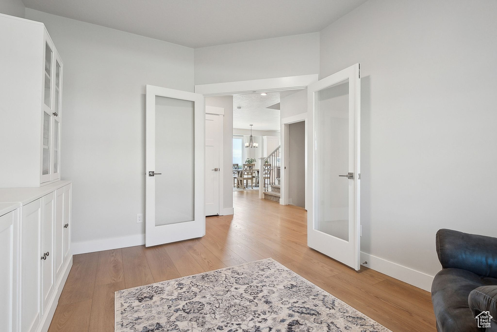 Living area featuring french doors, a chandelier, and light wood finished floors