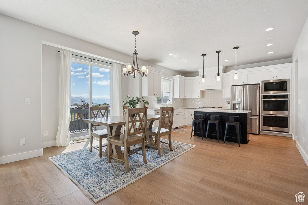 Dining room with a chandelier, light wood-style floors, baseboards, and recessed lighting