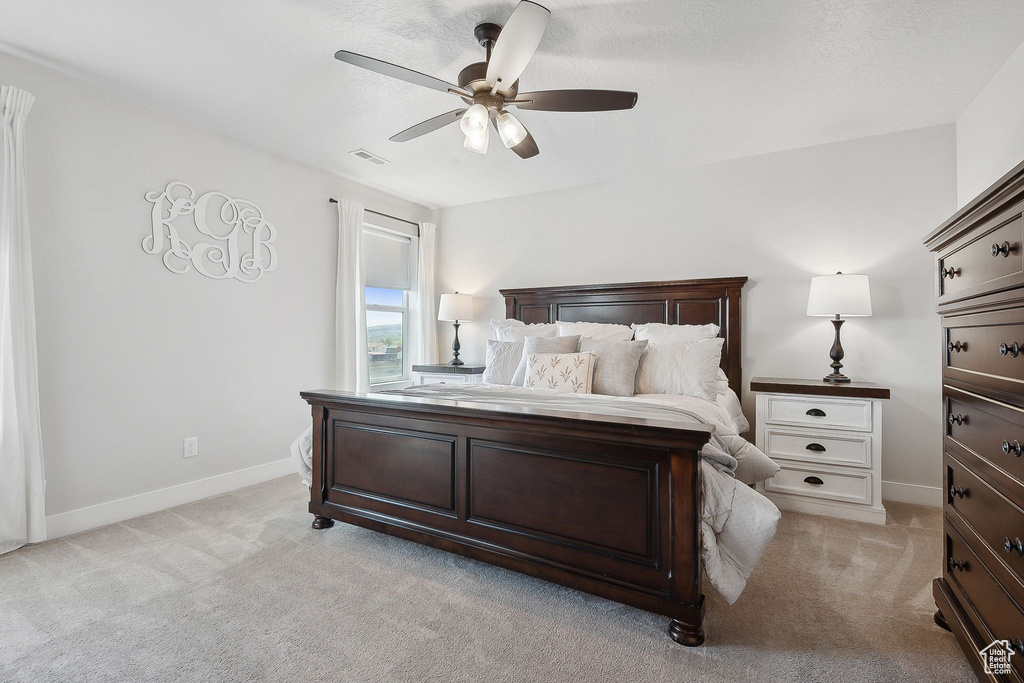 Bedroom with light colored carpet, baseboards, and a ceiling fan