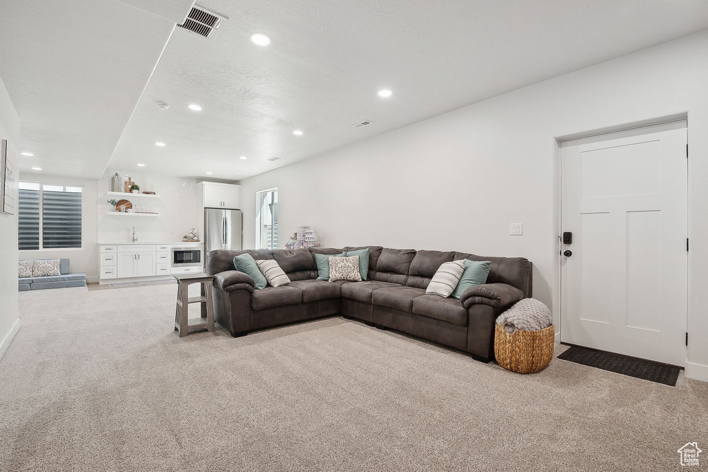 Living area featuring light carpet, recessed lighting, and bar area