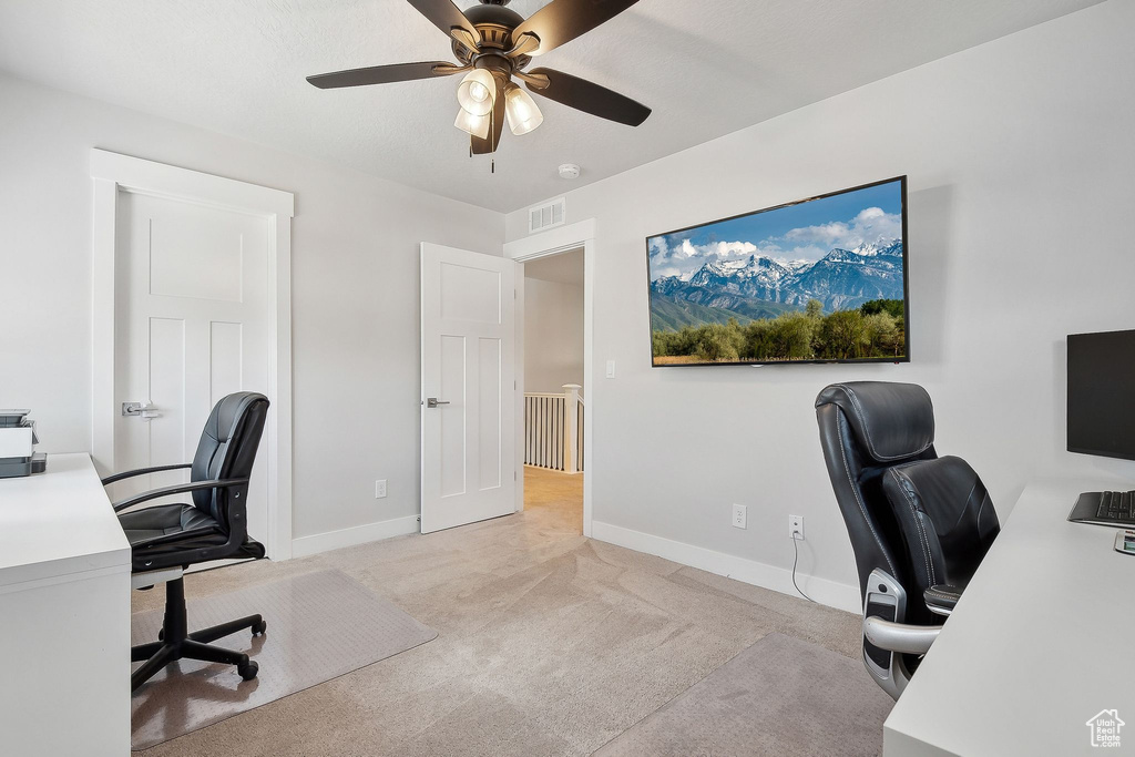 Office space featuring light carpet, a ceiling fan, and baseboards