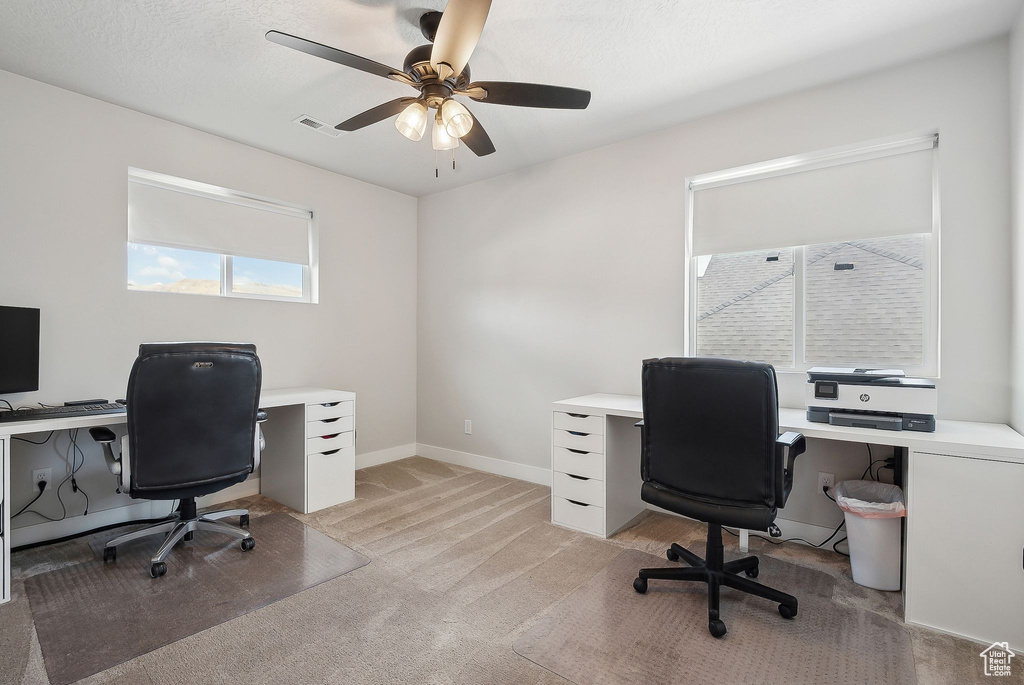 Home office featuring ceiling fan, light colored carpet, and baseboards