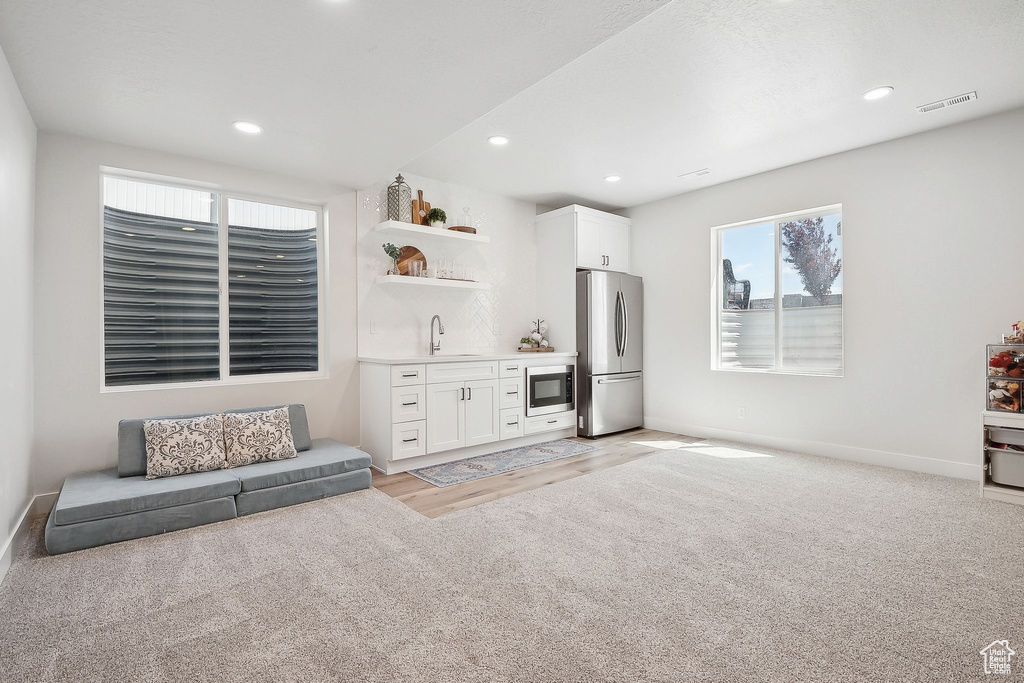 Living area with wet bar, healthy amount of natural light, baseboards, recessed lighting, and light wood-style flooring