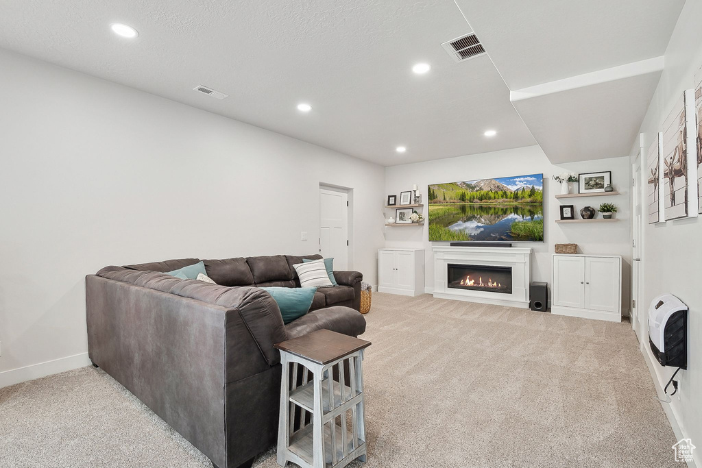Living room featuring carpet flooring, a glass covered fireplace, recessed lighting, baseboards, and heating unit
