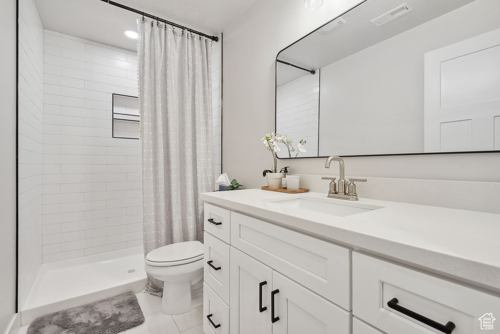 Full bathroom with toilet, vanity, and a tile shower