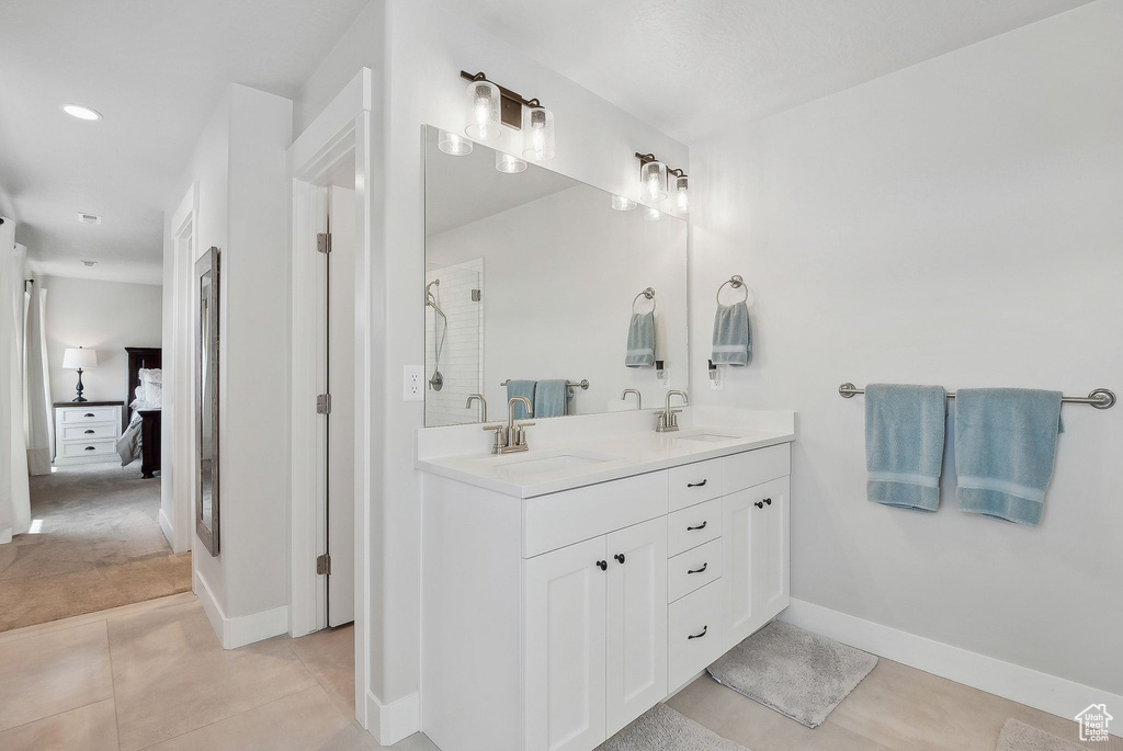 Ensuite bathroom featuring double vanity, tile patterned floors, baseboards, and a shower