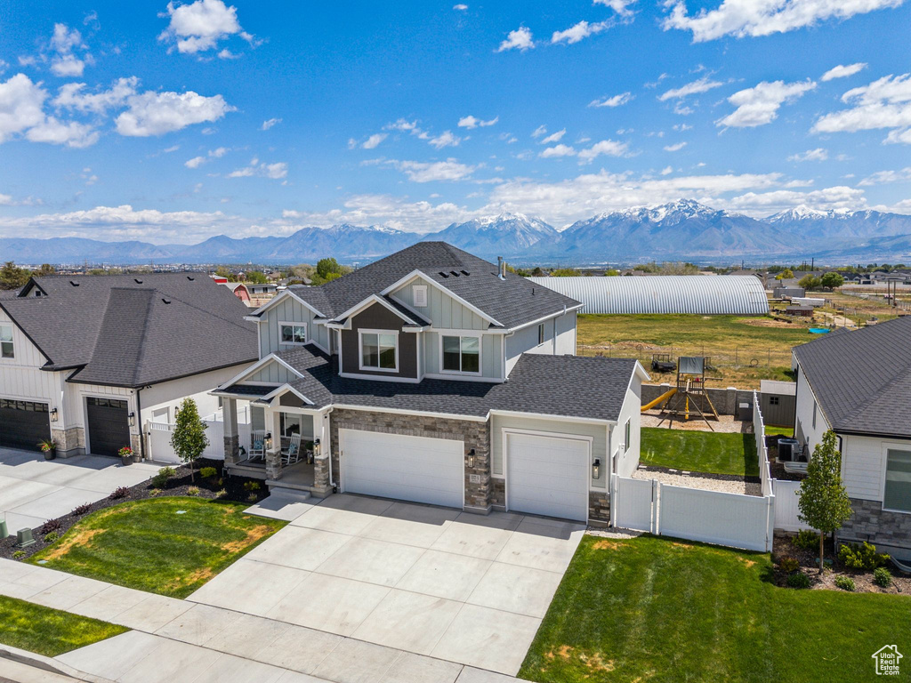 View of front of property featuring board and batten siding, a mountain view, a gate, stone siding, and driveway