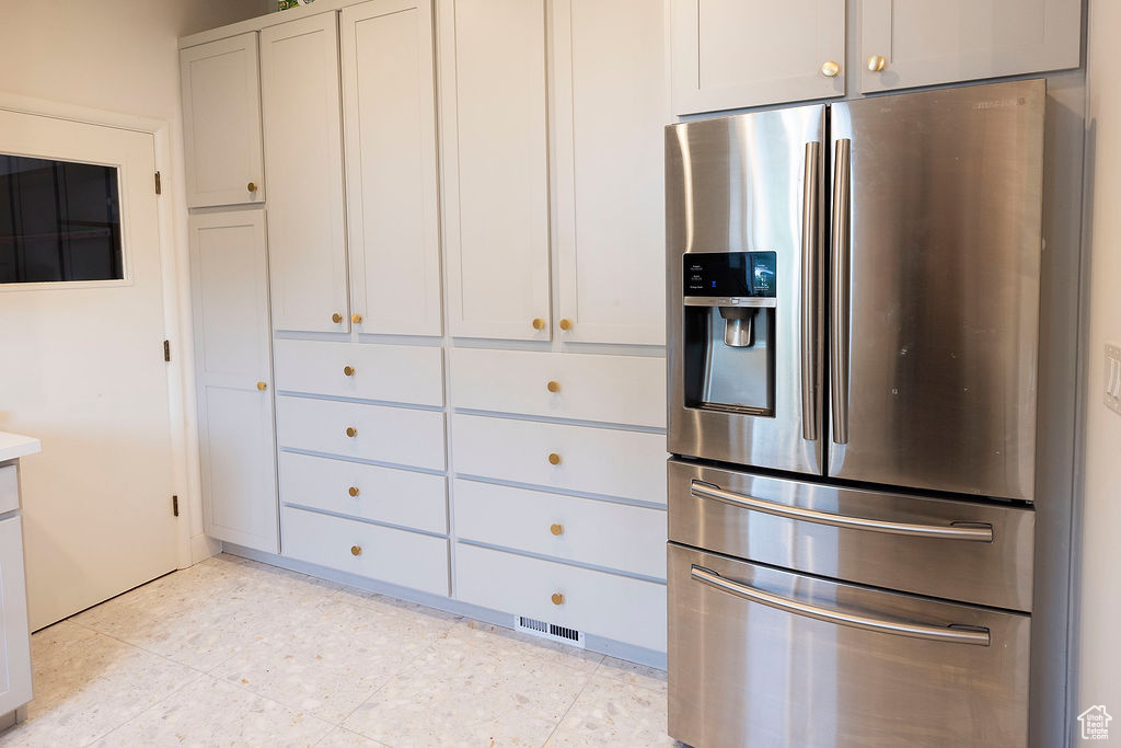 Kitchen with stainless steel fridge with ice dispenser, light countertops, and light tile patterned flooring