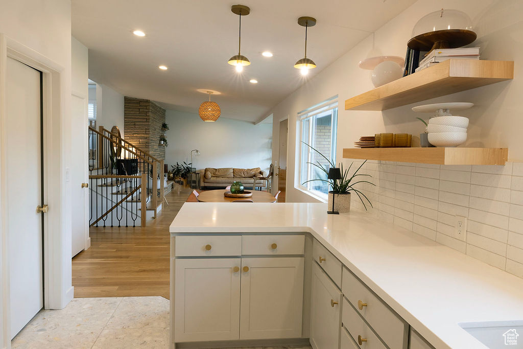 Kitchen featuring a peninsula, recessed lighting, light countertops, decorative light fixtures, and tasteful backsplash