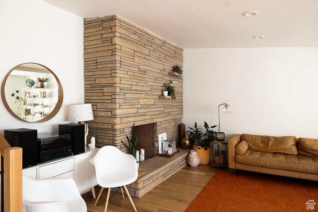 Living room with wood finished floors, a stone fireplace, and recessed lighting