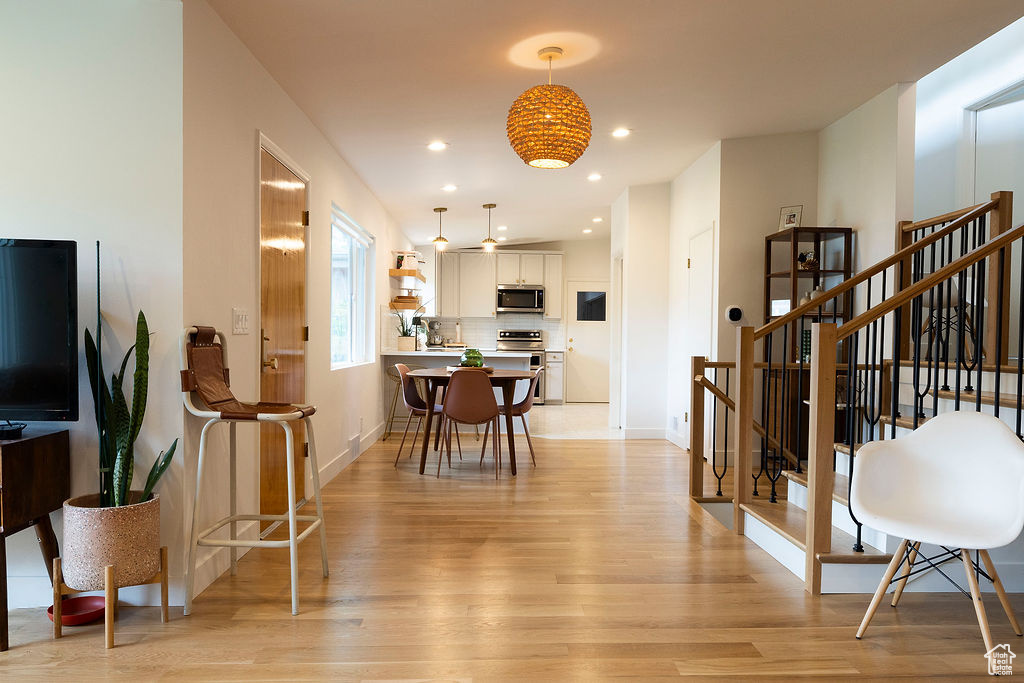 Living room featuring light wood-type flooring, stairway, baseboards, and recessed lighting