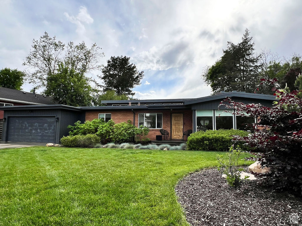 Ranch-style home with a garage, a front yard, and brick siding