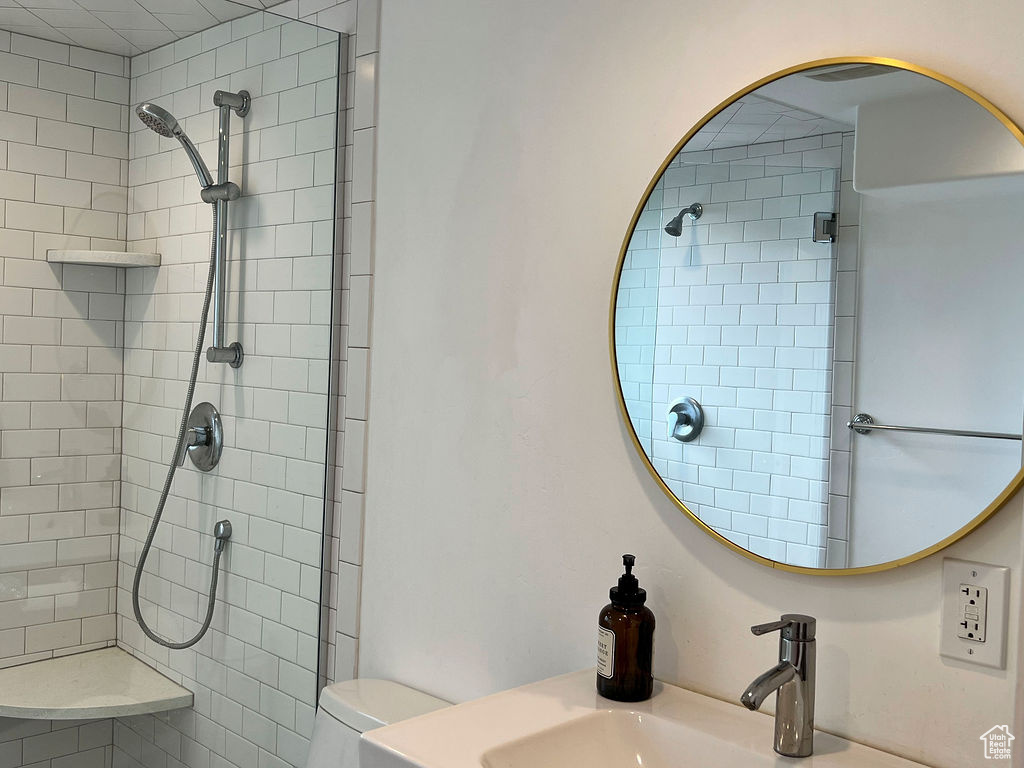 Full bathroom featuring tiled shower, toilet, and a sink