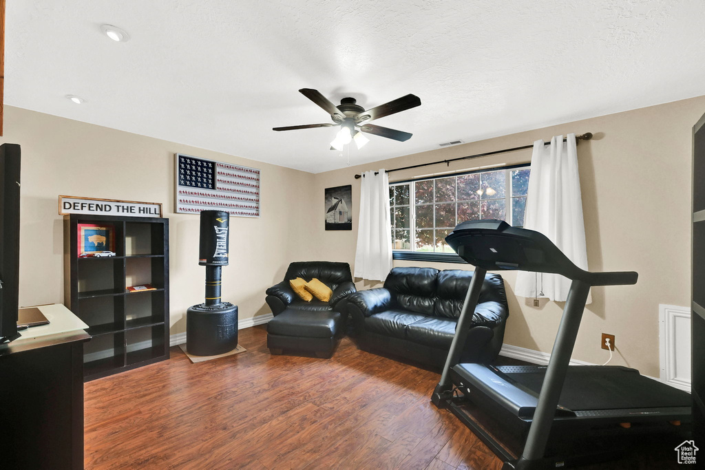 Exercise room with a ceiling fan, wood finished floors, and baseboards