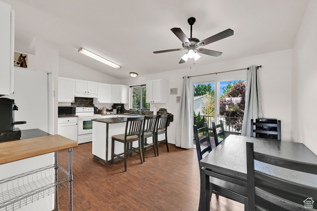 Kitchen with electric range, vaulted ceiling, white cabinetry, a ceiling fan, and dark wood-type flooring