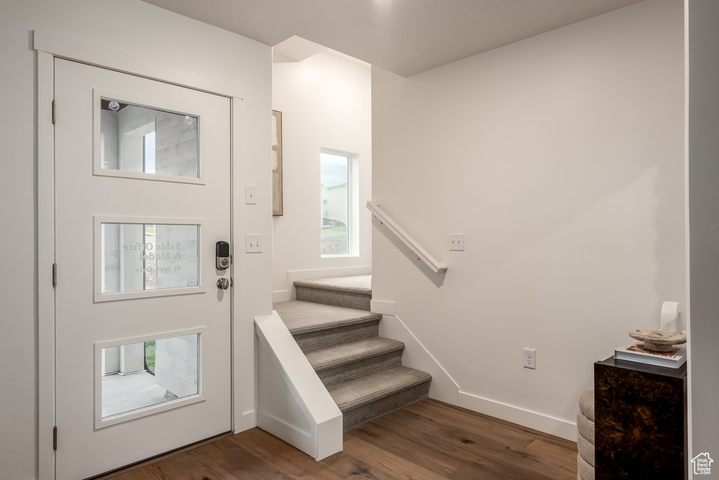 Foyer entrance featuring wood finished floors, stairs, and baseboards