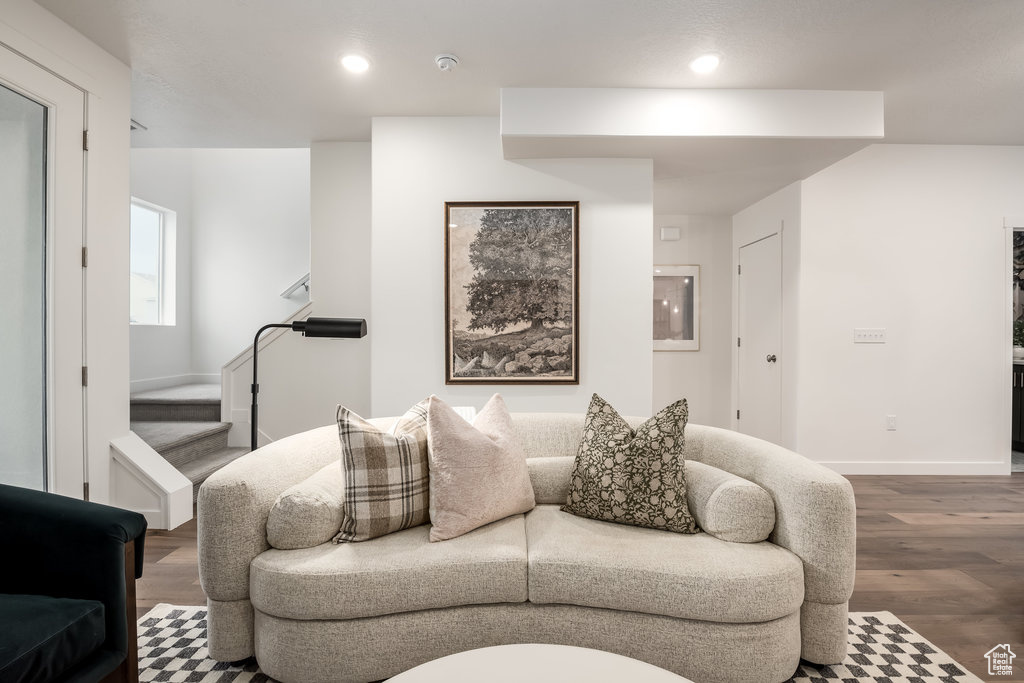 Living area with wood finished floors, baseboards, recessed lighting, and stairway