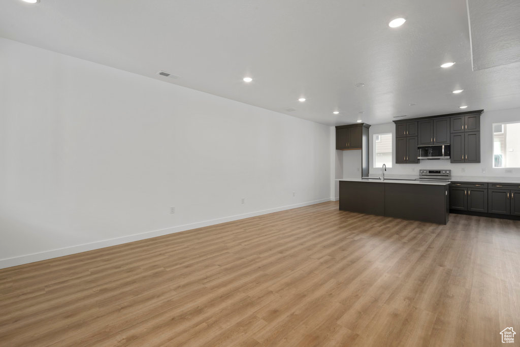 Unfurnished living room featuring light wood finished floors, recessed lighting, baseboards, and a sink