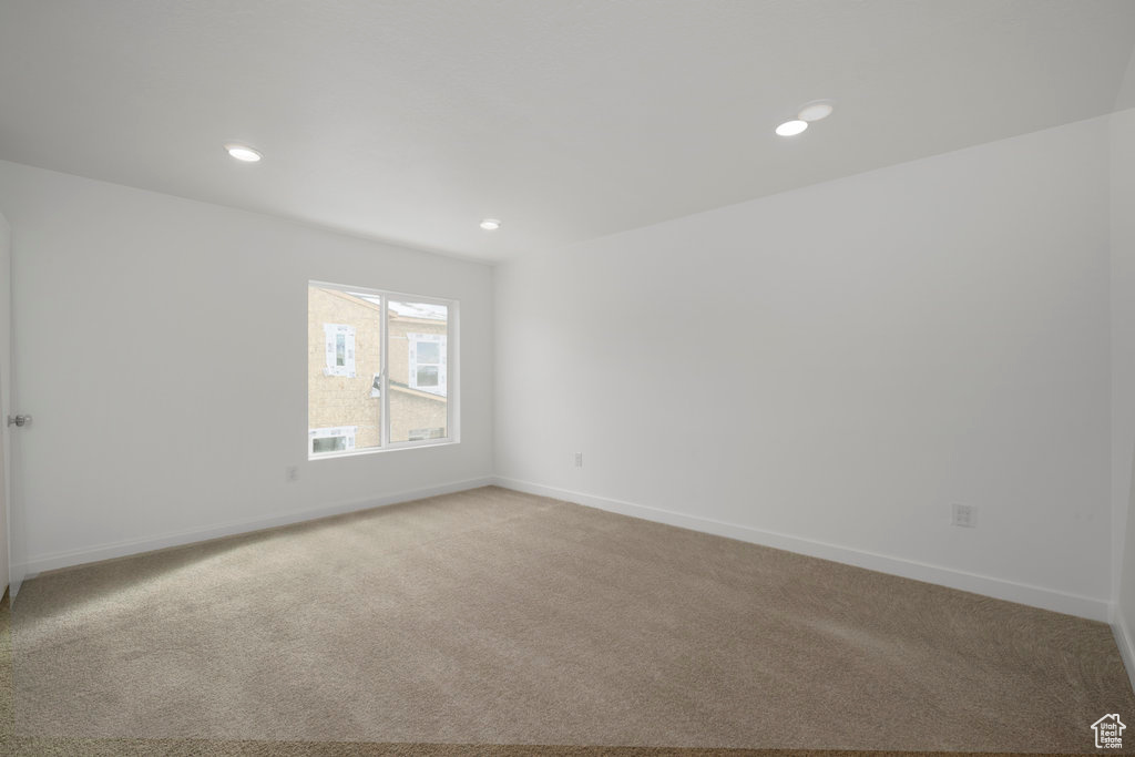Empty room featuring light colored carpet, baseboards, and recessed lighting