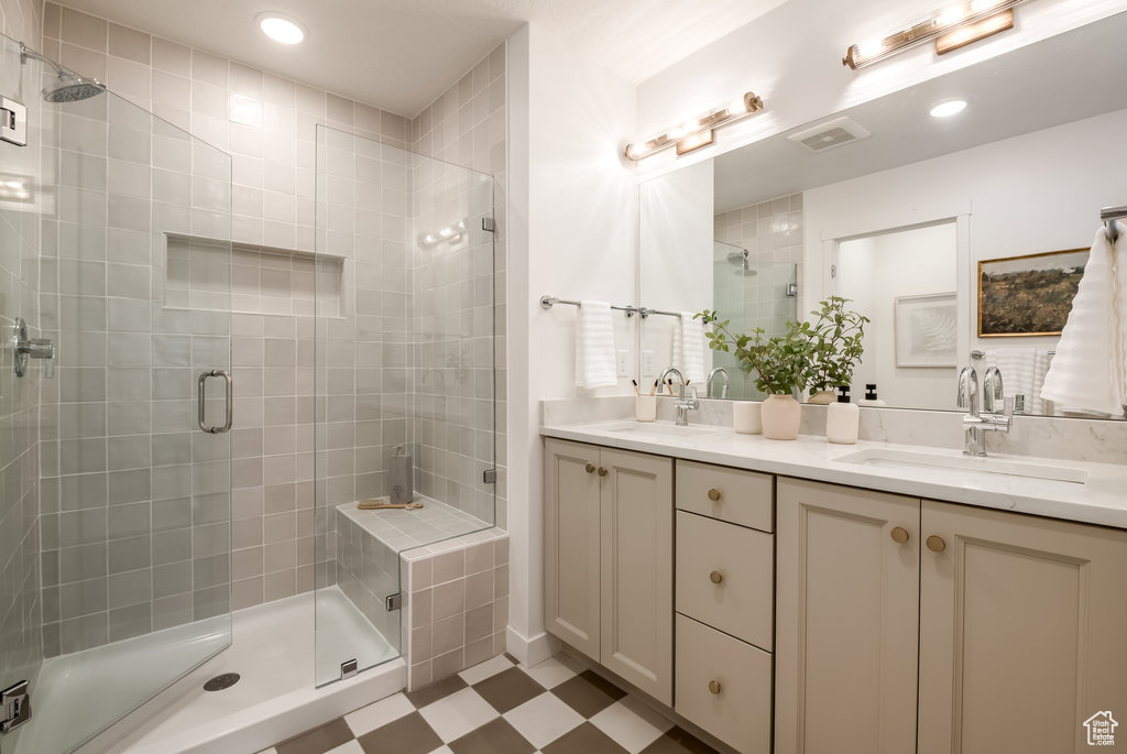 Full bath featuring double vanity, a shower stall, tile patterned floors, and recessed lighting